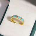 Detailed macro view of the gold-toned flower enamel ring inside a velvet jewelry box - Light Blue