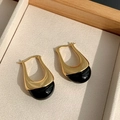 Primer plano de pendientes irregulares de metal dorado y chocolate en base rugosa - Negro