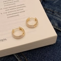 Elegant gold hoop earrings with white inlay resting on a book for a minimalist aesthetic - White