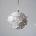Close-up of a white petal-shaped Christmas ball with glitter and hanging silver loop - Flower Bud Style / 8cm