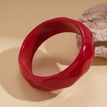 Artistic close-up of a bold red geometric resin bangle resting on a natural stone - Bright Red Geometric Faceted