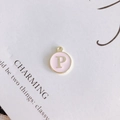 Close-up of golden round pendant with pink enamel and a gold letter P charm - Letter P