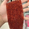 Strand of faceted orange-red carnelian beads held to show texture and light clarity - Red Agate 3mm