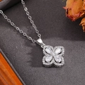 Gros plan d'un pendentif fleur argenté serti de zircons sur un écrin à bijoux en velours - Collier Fleur à Quatre Feuilles Ajourée Argenté (T024)