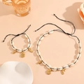 Detail view of beach style shell necklace and bracelet set with golden sea life charms - Black Rope Conch Set