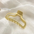 Matte gold hollow geometric metal claw clip for thick hair displayed on white fabric - Matte Gold Metal Claw