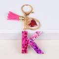 Detail of glittery letter K keychain with rose red tassel and small heart charm - Letter K