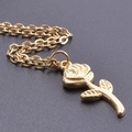 Macro shot of detailed golden rose pendant with delicate chain on dark background - Necklace / Gold