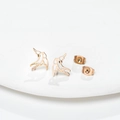 Minimalist golden hollow bird stud earrings in stainless steel on white tray - Rose Gold