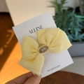 Detail of a creamy yellow linen bow hair clip with a brown oval accent on a display card - Creamy Yellow Bowknot Duckbill Clip