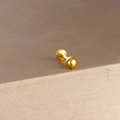 Macro-opname van een gepolijste gouden labret piercing op luxe zijdeglans satijn - Gouden Gepolijste Balvorm
