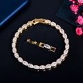 Elegante gouden zirkoon armband met ovale stenen en verlenging op donkere textuur - Goud