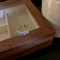 Detail of silver-colored layered open ring with sparkling cubic zirconia on wood frame - Wavy Straight Intertwined Style (WR271) / Silver