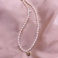 Elegant freshwater pearl necklace with a golden heart pendant on pink satin background - Heart of Star