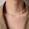 Dettaglio della collana di perle naturali placcata in oro 14K sul collo di una modella - Choker con Perle di Riso Bianche (TAT-607)