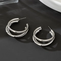 Vue détaillée des boucles d'oreilles doubles créoles argentées sur fond noir texturé - Argenté
