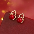 Vista macro di orecchini a forma di zucca dorata con perle rosse e zirconi - Stile Fiocco a Forma di Zucca con Perle Rosse (Perno in Argento S925)