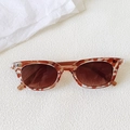 Detailed view of tortoiseshell cat-eye sunglasses on a textured minimalist background - Brown Spotted