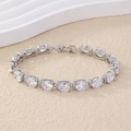 Silver-toned bracelet with oval cubic zirconia stones on textured beige surface - Oval Halo Style (B00331) / White
