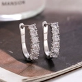 Orecchini huggie in argento con zirconi tondi su sfondo minimalista di una rivista - Argento