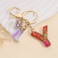 Detail of colorful glitter letter Y keychain with purple tassel and gold ring on white pedestal - Letter Y