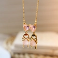 Close-up of golden necklace featuring pink heart stones and twin girl charms details - Girl (Pink)