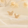 Exquisite gold butterfly stud earrings with zircon inlay on a warm textured background - Gold
