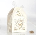 Macro shot of off-white laser-cut heart favor box with a translucent white silk ribbon - Ivory