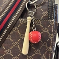 Close-up of a mini wooden baseball bat keychain with a red leather ball on a handbag - 7.5CM Long Bat/Red Ball