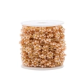 Macro detail of 1.5mm gold plated flat chain with woven peach crystal flowers on a roll - Yellow Brown