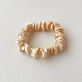 Macro-opname van champagne gouden satijnen scrunchie met glanzende zijden textuur - Broken Wit