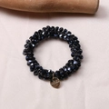 Detail of black crystal beaded hair tie with gold round metal pendant on silk fabric - Navy Blue