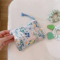 Close-up of mini floral cotton pouch with rabbit pattern and blue woven zipper pull - Blue Green Floral