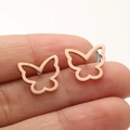 Macro detail of rose gold butterfly earrings displayed on fingers showing texture - 670 Hollow Winged Butterfly / Rose Gold
