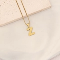 Golden letter Z pendant necklace with honeycomb texture on a stone surface - Letter Z