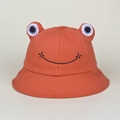 Detail of brick red frog bucket hat featuring 3D eyes and black embroidered smile - Brick Red