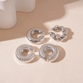 Detalle macro de pendientes de clip en C plateados con texturas metálicas lisas y trenzadas - Juego de Plata (4 Piezas)