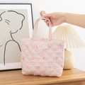 Close-up of pink checkered quilted cosmetic bag with delicate floral bow patterns - Pink Grid with Bow