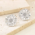 Macro shot of silver floral earrings with petal textures on beige textured stone - 3D Silver Flower Style (KE114948-KFC)