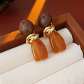 Détail macro de boucles d'oreilles vintage en bois et résine ambre dans un écrin à bijoux - Tige d'oreille en argent sterling 925 - Café