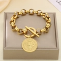 Close-up of gold chain bracelet with round portrait pendant and OT toggle clasp on display - Gold Bracelet