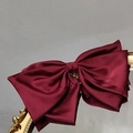 Detail view of large burgundy satin bow hair clip on a vintage mirror surface - Burgundy