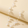 Close-up of layered gold chain necklace featuring multiple white faux pearls on beige stand - White
