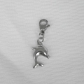 Close-up of a jumping silver dolphin pendant with lobster clasp on white fabric - Large Dolphin