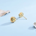 Macro view of gold-plated roman numeral stud earrings with champagne round gemstones - Yellow