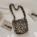 Vista piatta di una borsa a spalla in peluche leopardato con accessori su tessuto bianco - Leopardo Crema