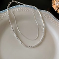 Detail of layered silver necklaces with small cube beads on a decorative ceramic plate - Silver Double Layer Broken Silver Necklace