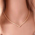 Close-up of elegant gold V-shaped necklace with shimmering cubic zirconia on neck - Gold Necklace