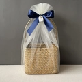 Detail of seagrass basket wrapped in white mesh with a navy blue ribbon bow and gift tag - Navy Blue Full Wrap Snow Mesh