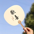 Miniature Chinese calligraphy fan with Huanxi text against a clear blue sky background - Happiness